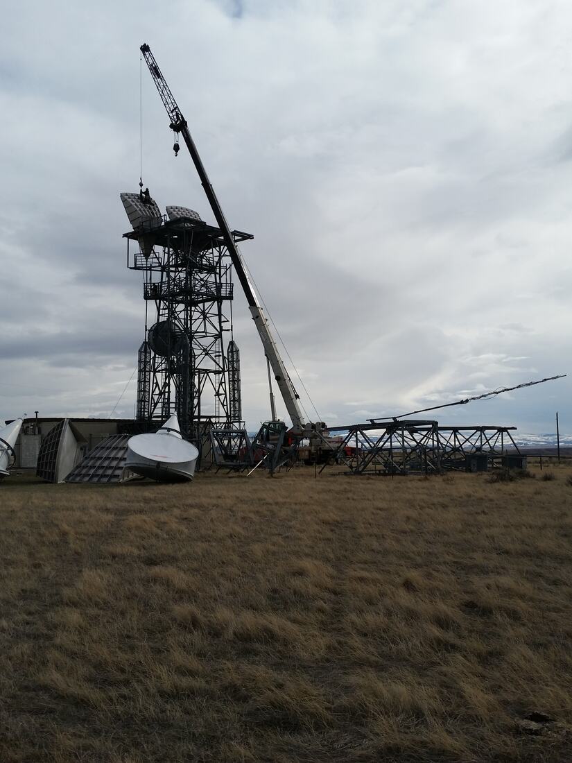 Crane working a tower during a structural modification, dish removed to grade