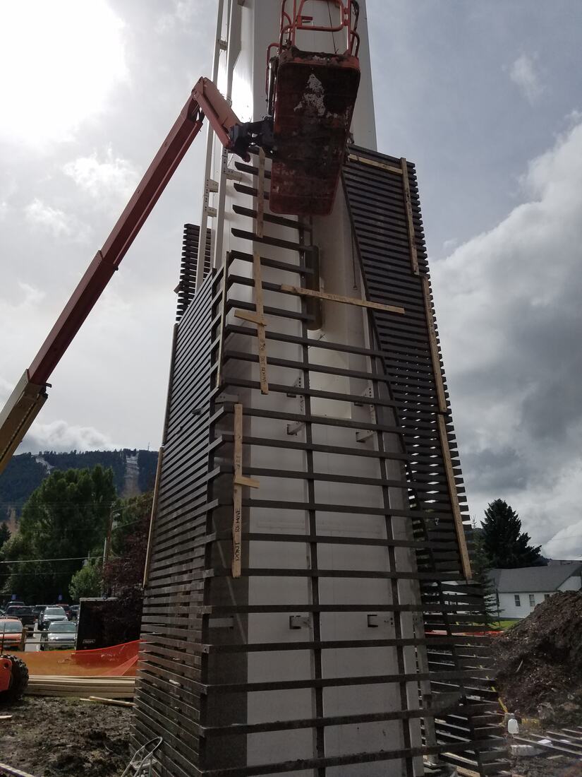 Screening panels being installed around a monopole from a boom lift