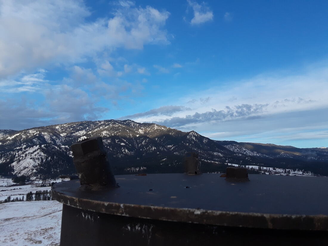 Top flange of a monopole with a snow-covered mountain valley beyond
