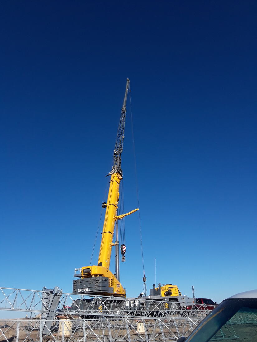 Crane boom extended beside a tower under construction