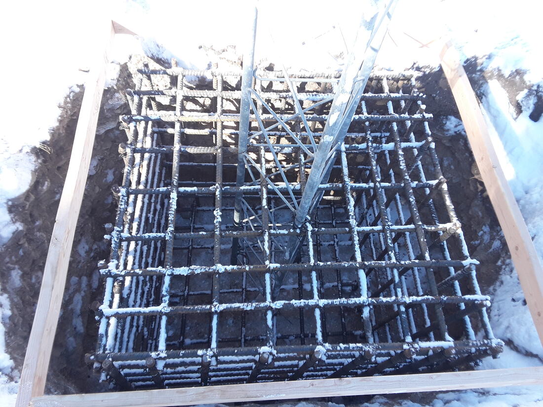 Rebar cage and tower stub set in a formed foundation in winter