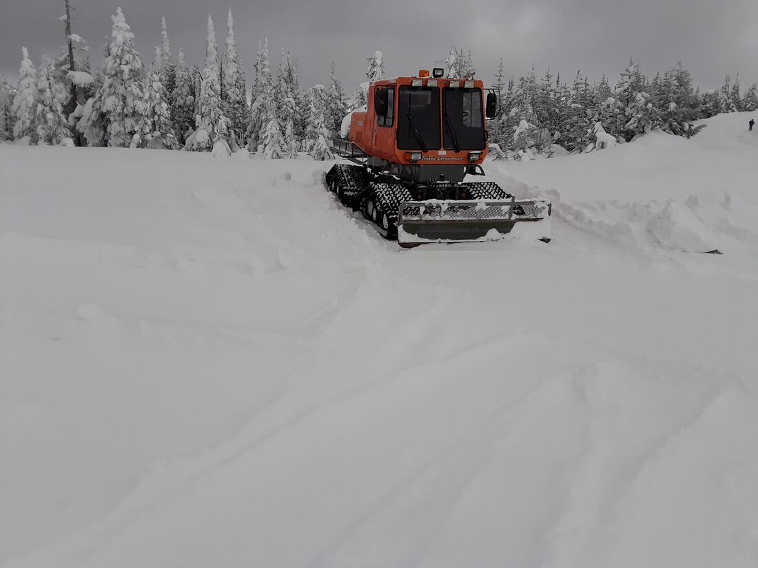 Tracked snowcat breaking trail to a snowbound mountaintop site