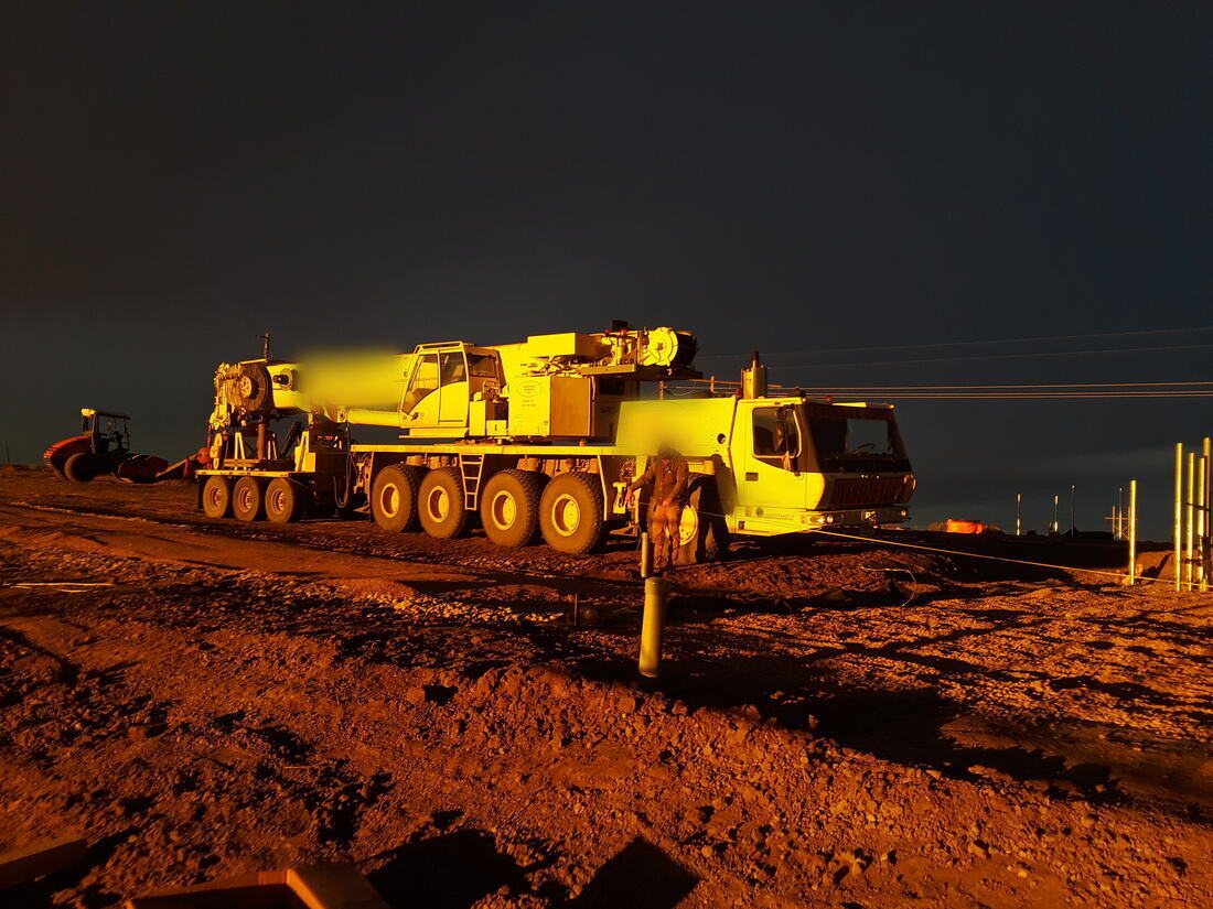 All-terrain crane on a tower site lit by the sunrise