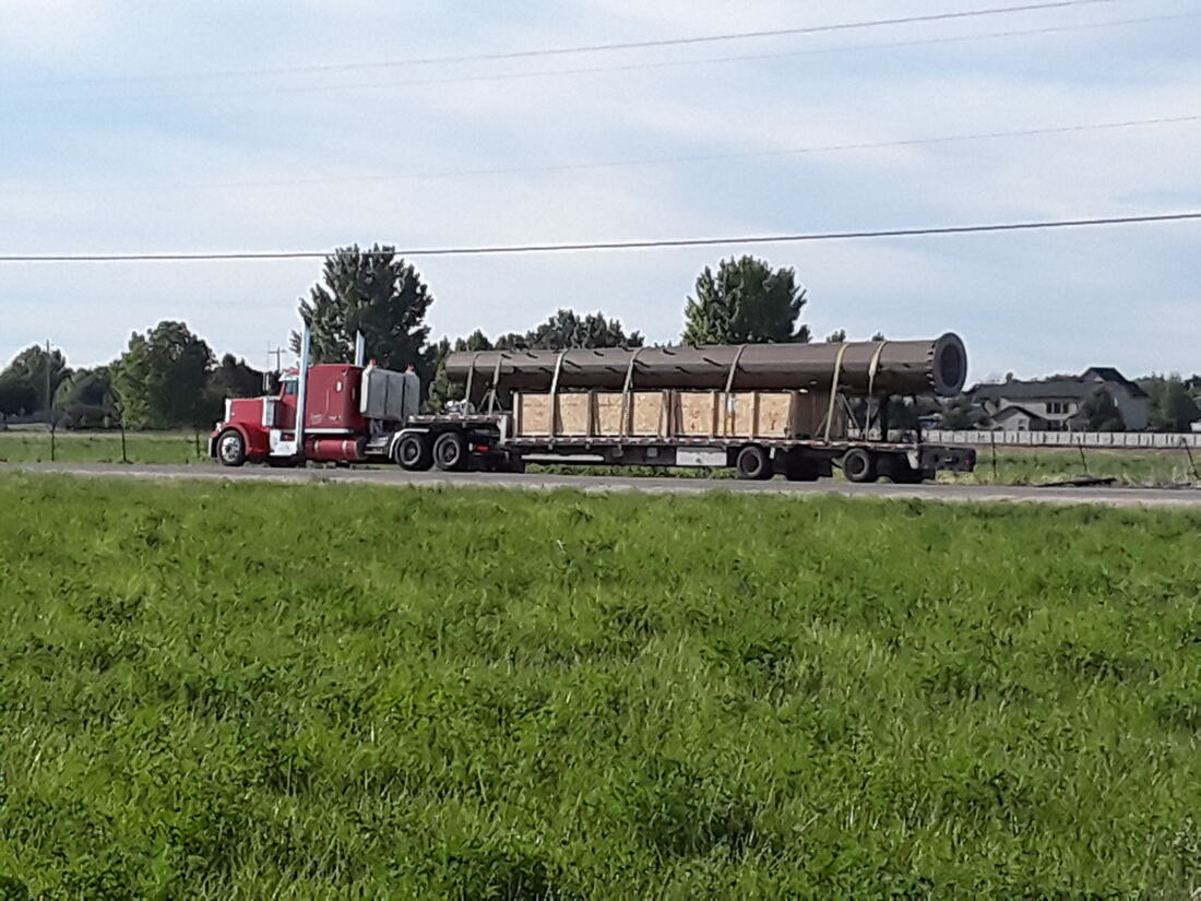 Semi truck delivering a monopole on a lowboy trailer