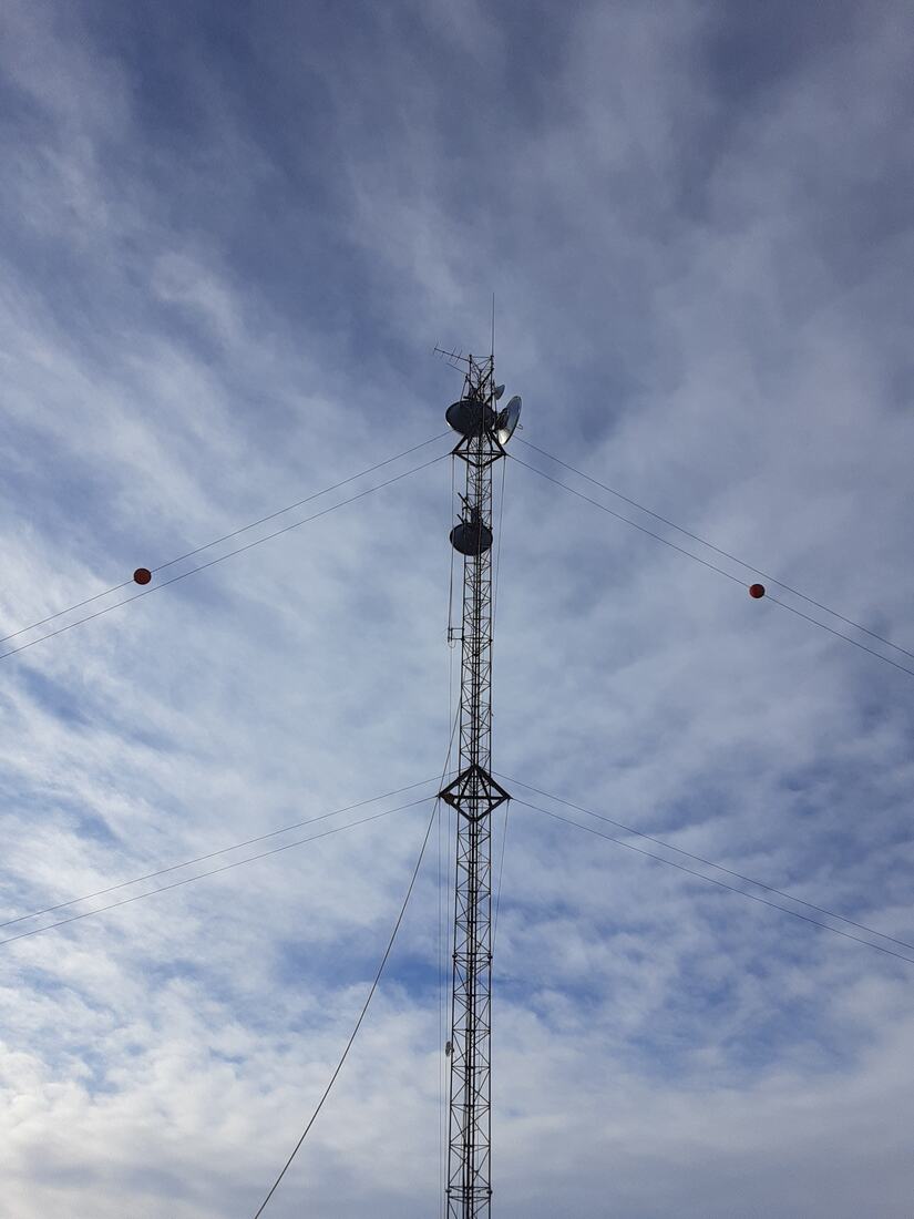 Guyed tower carrying microwave dishes against high cloud